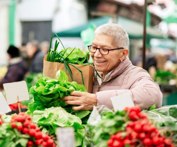 Smiling elderly woman shopping for food.